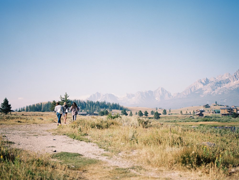 Image of blue skies, scenic mountain views, green grass, and gravel road of this Stanley Idaho Wedding.
