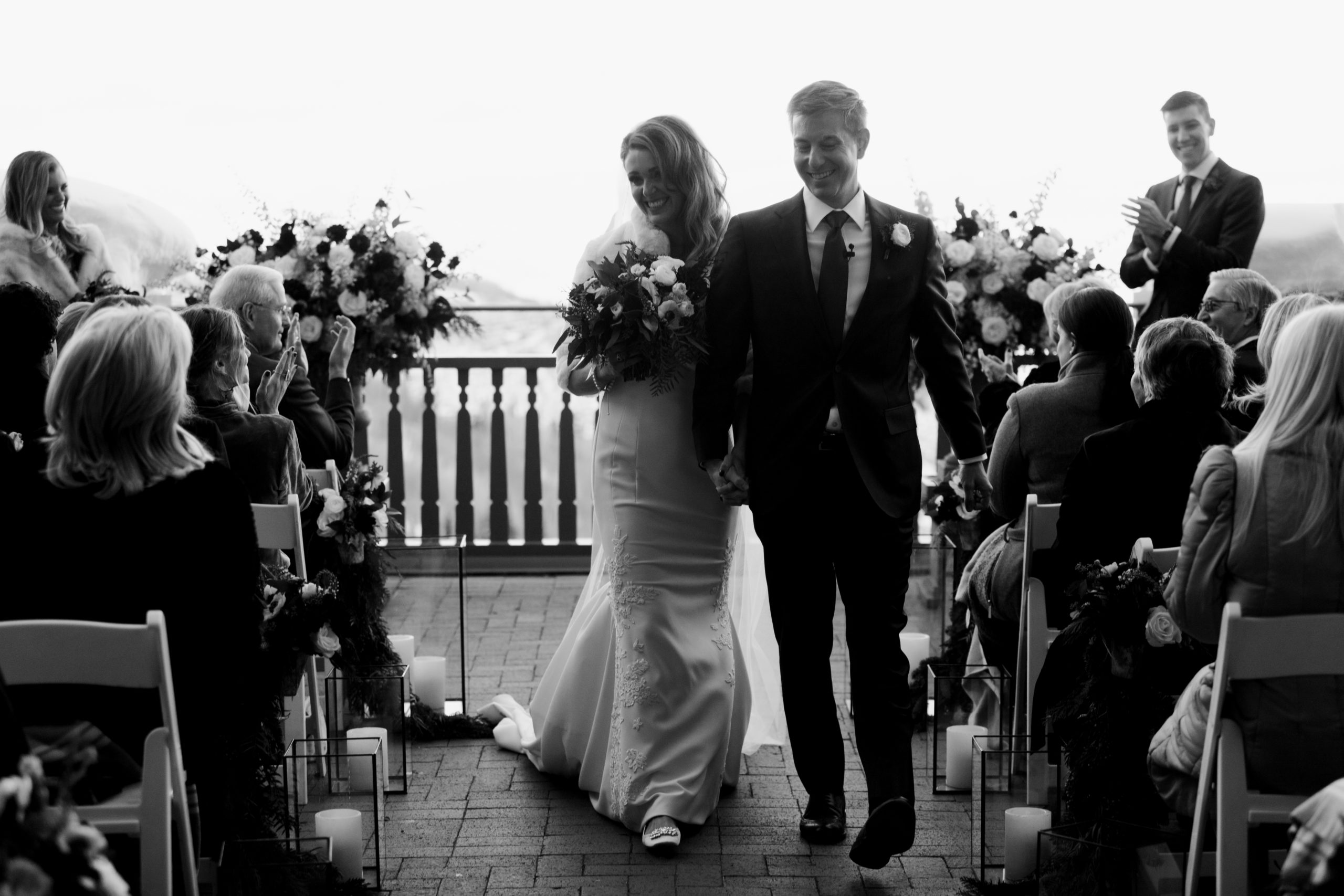 The bride and groom walk down the aisle after their ceremony is finished. This black and white picture captures the couple smiling at the guests. A dream Park City winter wedding.
