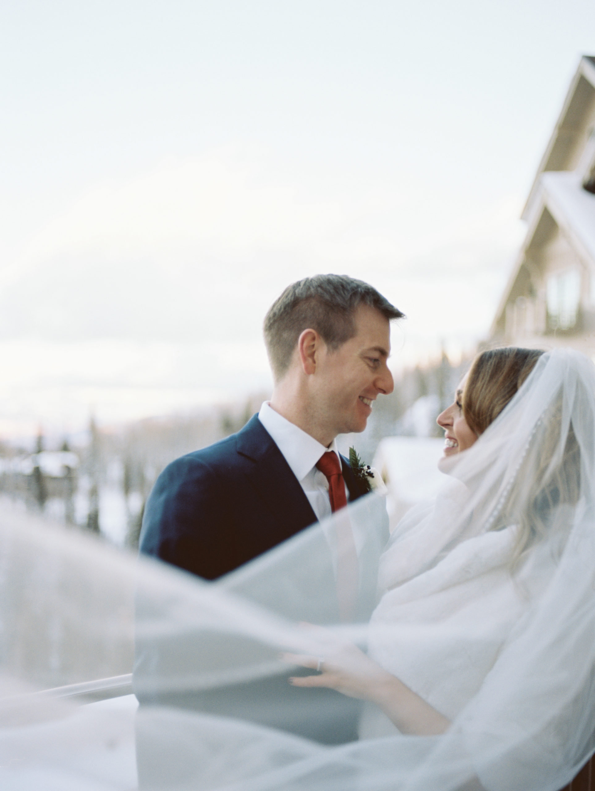 A picture zoomed in of the bride and groom. They are staring into each others eye where you can clearly see their love. The bride's veil flows in front of them to create a beautiful contrast in the picture. A dream Park City winter wedding.