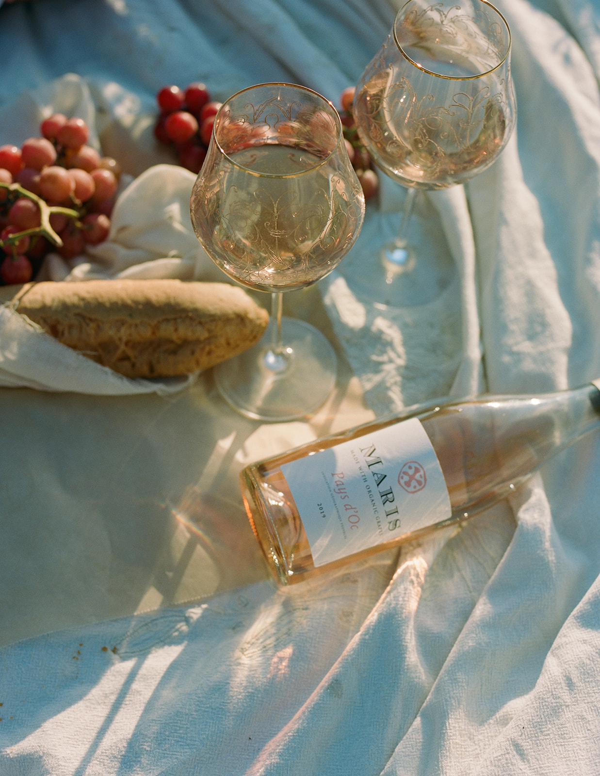 a summer picnic photoshoot of rose wine, french bread and glass wine cups.