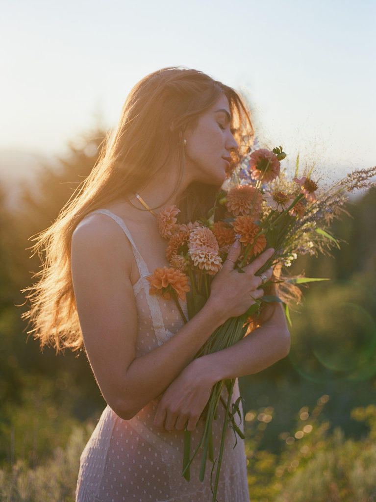Woman posing for a summer picnic shoot holding wildflowers. 