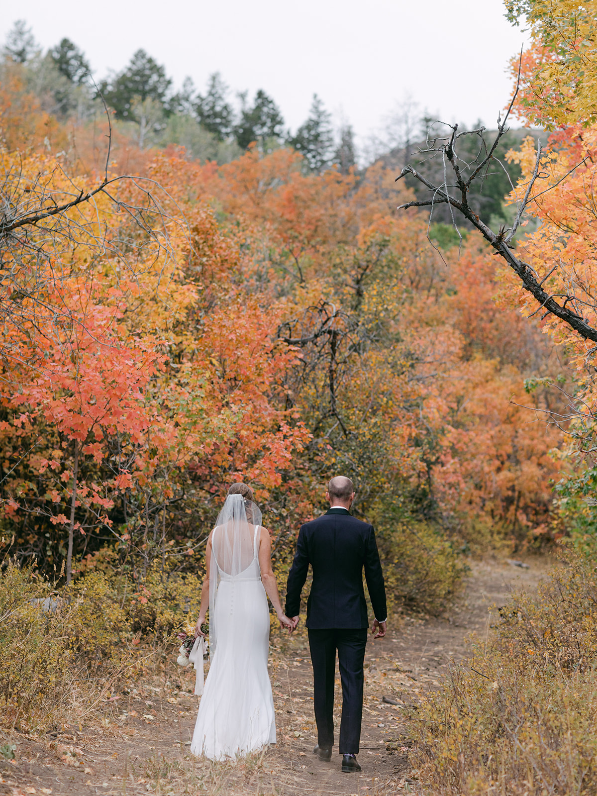 a rustic modern wedding in the high mountains of Utah. The bride is a caucasian female wearing a white crepe fabric wedding dress.
