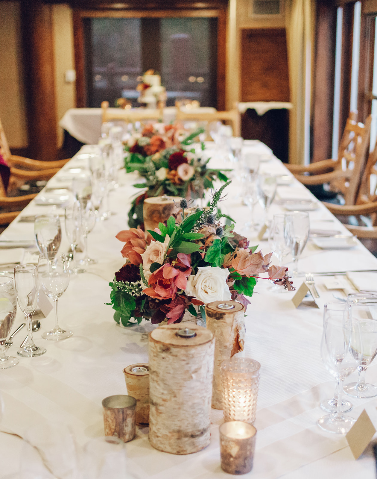 A fall wedding in Park City Utah. The tablescape features green, white, ad dark rose colored florals.