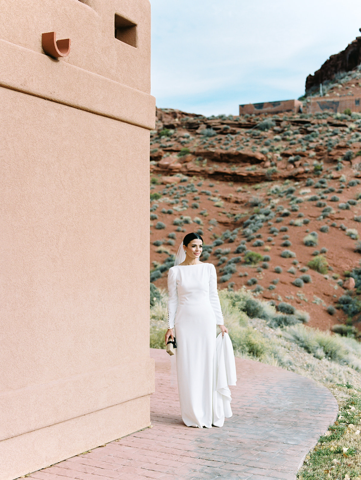 bride poses for wedding portraits in moab utah wearing a sleek long sleeve wedding gown