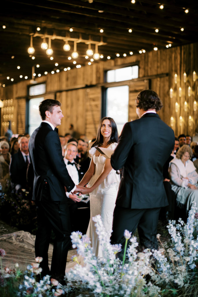a couple exchanges vows while their friends and family look on at an elegant ranch wedding in park city utah at the lodge at blue sky. photo by megan robinson photography 