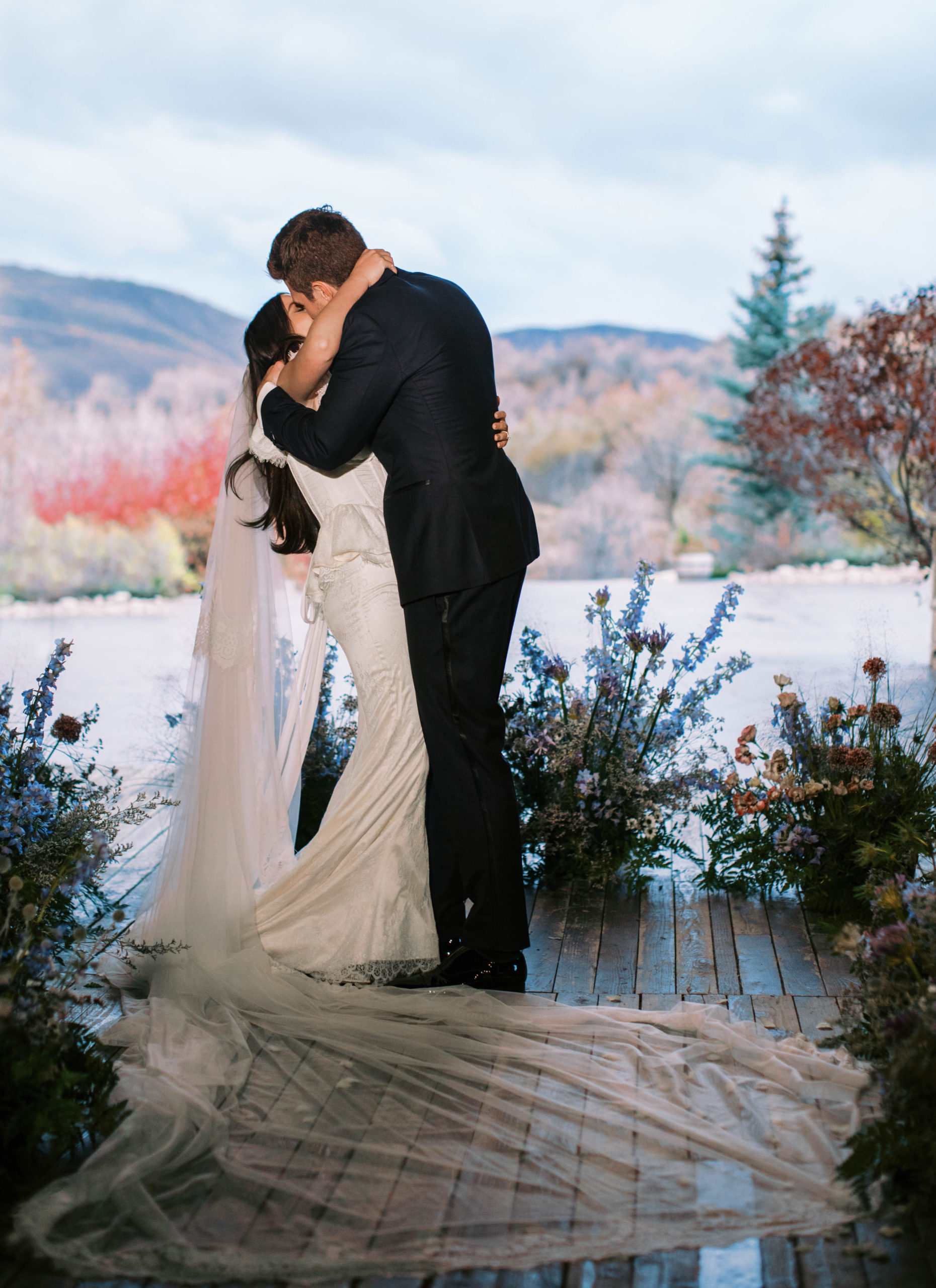 the bride and groom kiss at their wedding ceremony with mountains in the background at their blue sky ranch destination wedding in utah. photo taken by megan robinson photography