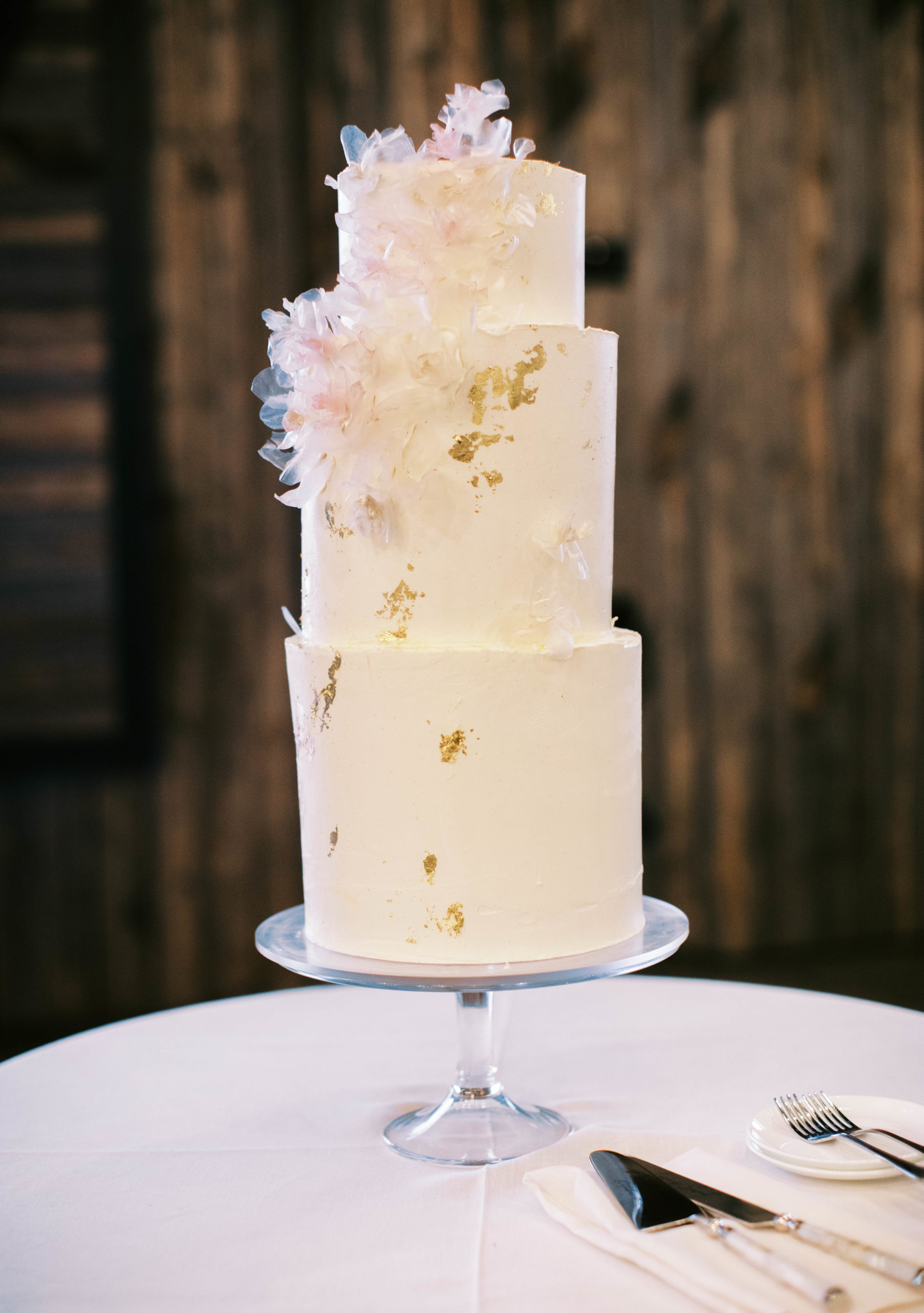 a white three tier wedding cake with gold accents for an eclectic blue sky ranch wedding in utah
