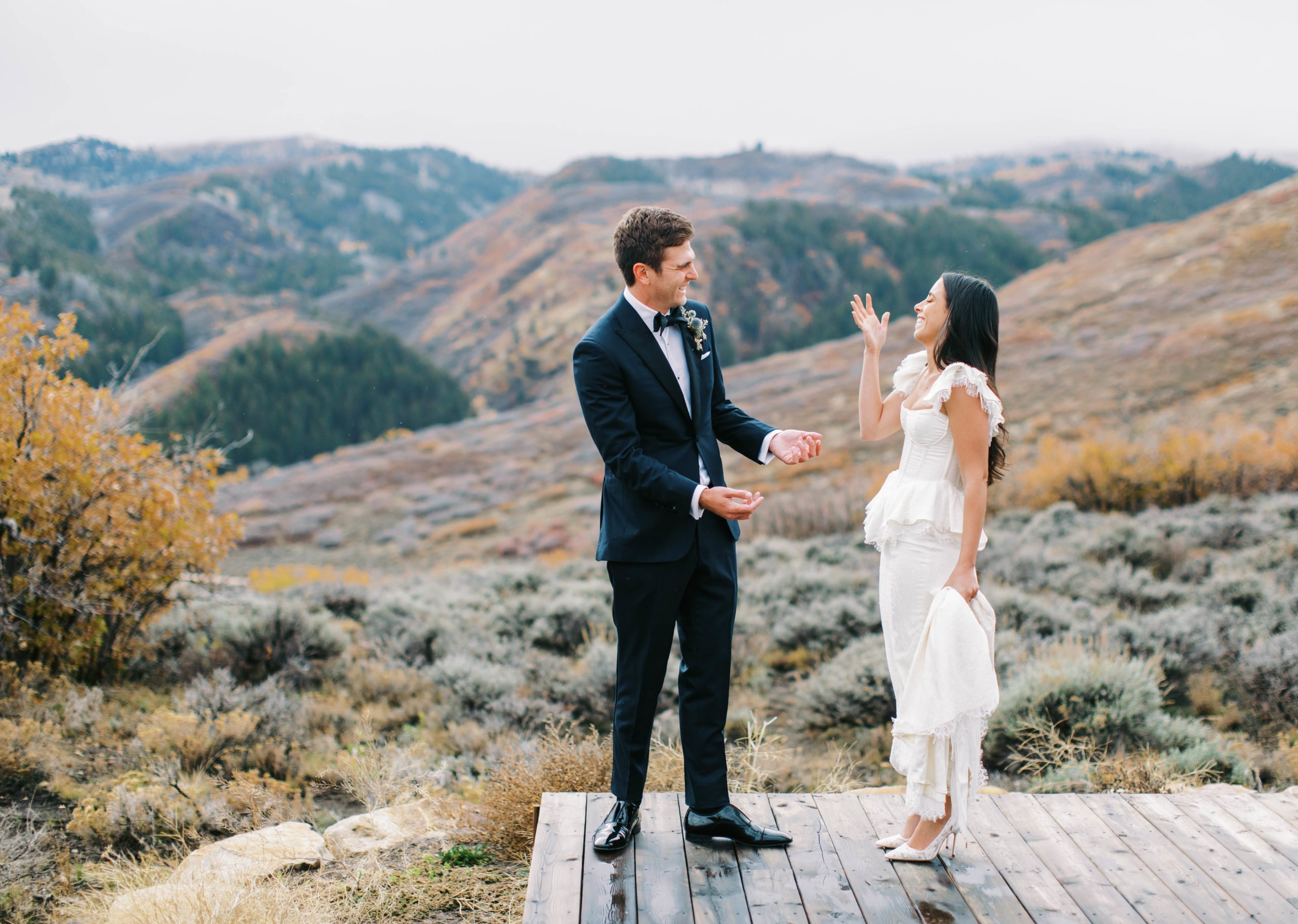 a bride and groom see each other for the first time on their wedding day. they laugh together with mountain views in the background. photo taken by megan robinson photography
