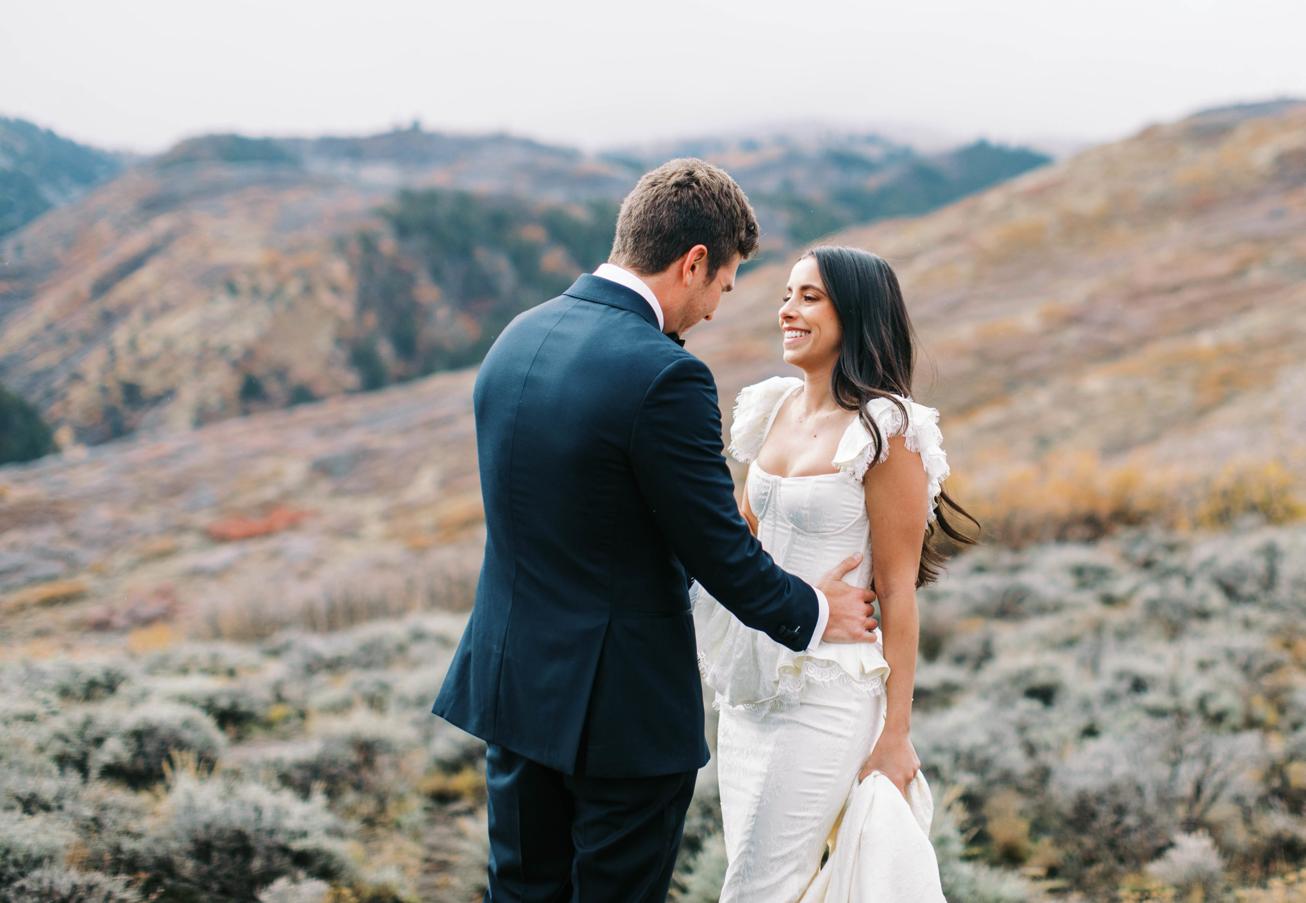 a groom looks at his bride in her vintage wedding gown at their fall utah ranch wedding. photo taken by megan robinson photography