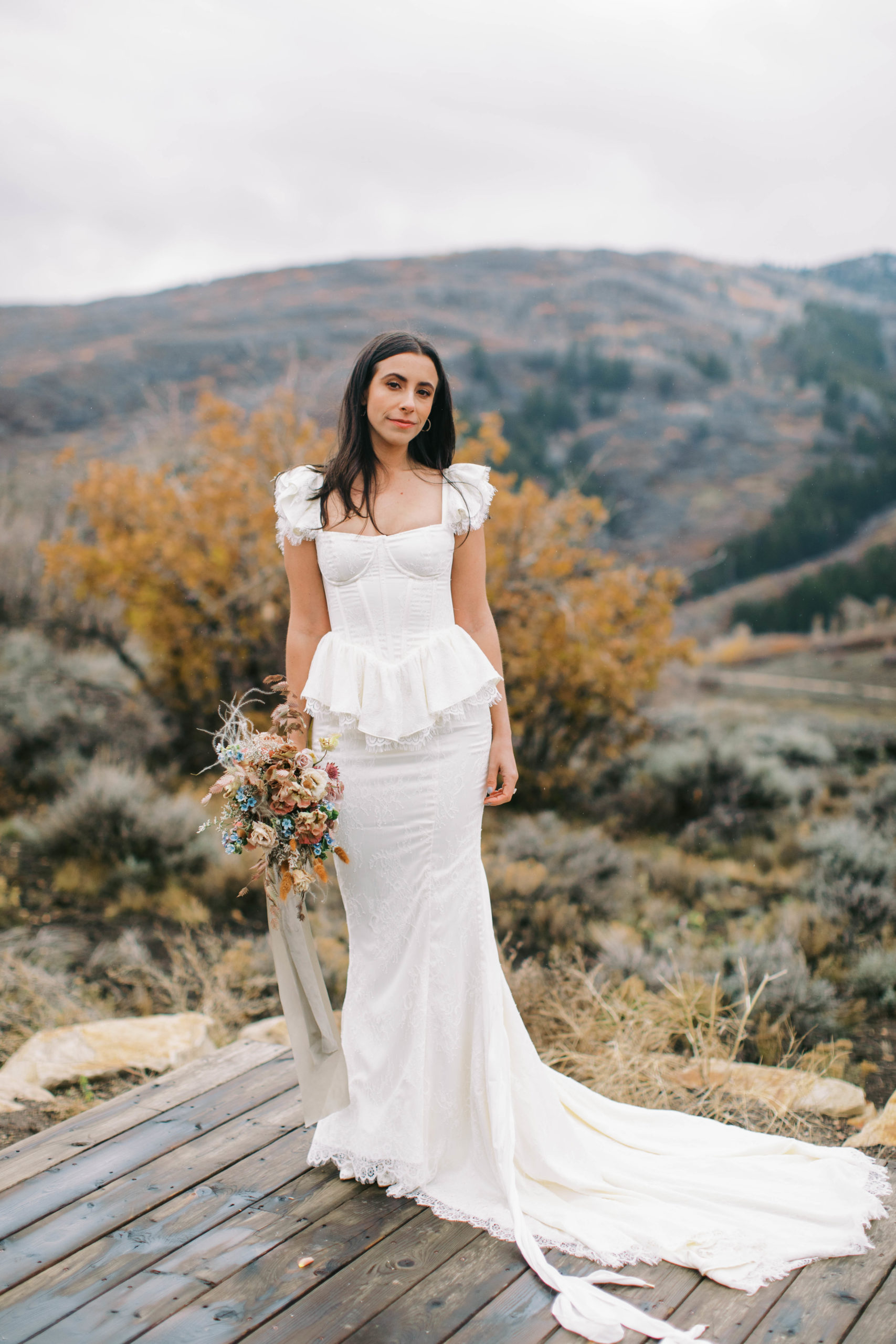 a bride wears a custom vintage wedding dress and carries a unique wedding bouquet at her eclectic ranch wedding in utah