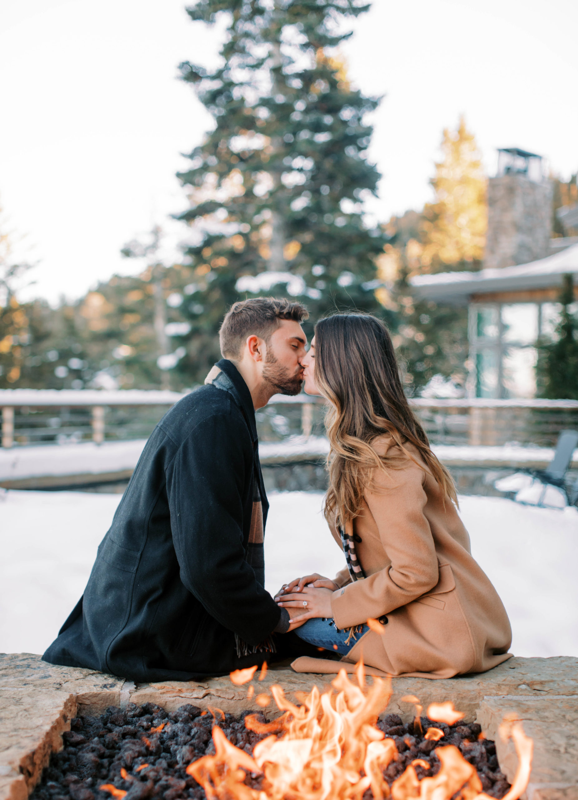 a couple kisses for outdoor winter engagement photos at stein eriksen lodge in park city utah. photo taken by megan robinson photography  