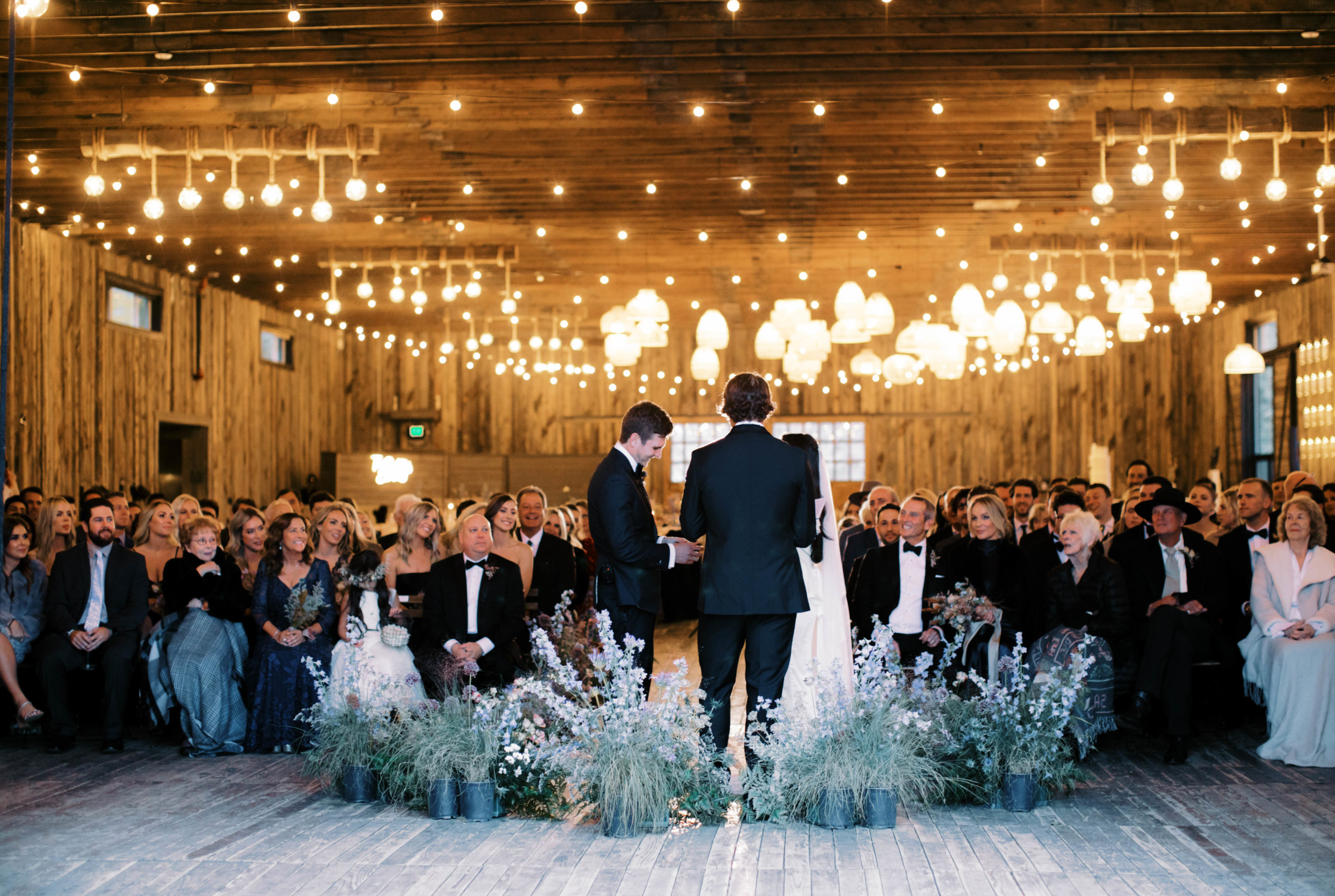 a couple exchanges vows while their friends and family look on at an elegant ranch wedding in park city utah at the lodge at blue sky. photo by megan robinson photography 