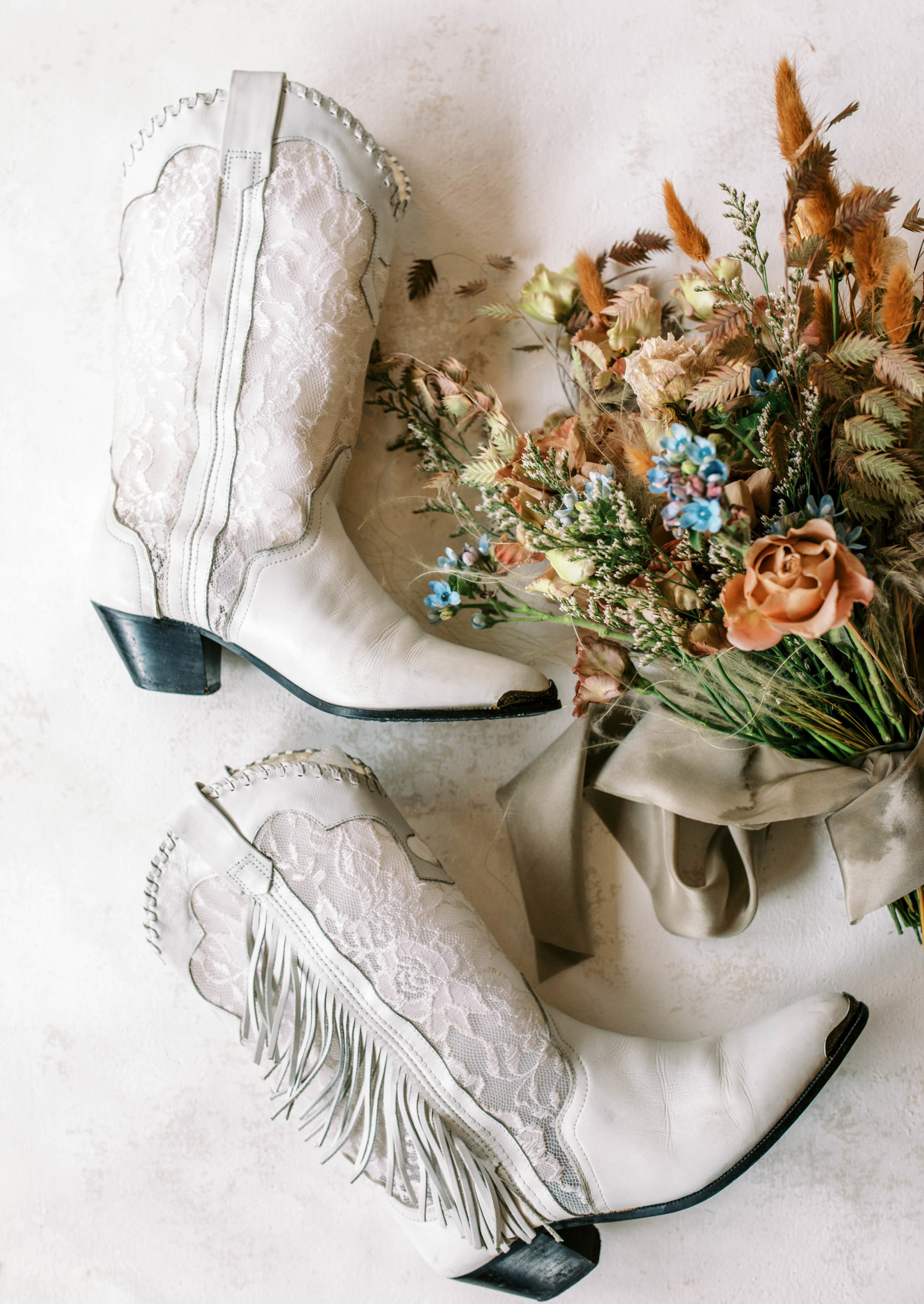 a brides white cowgirl boots and vintage wedding bouquet for a utah ranch wedding. photo taken by megan robinson photography
