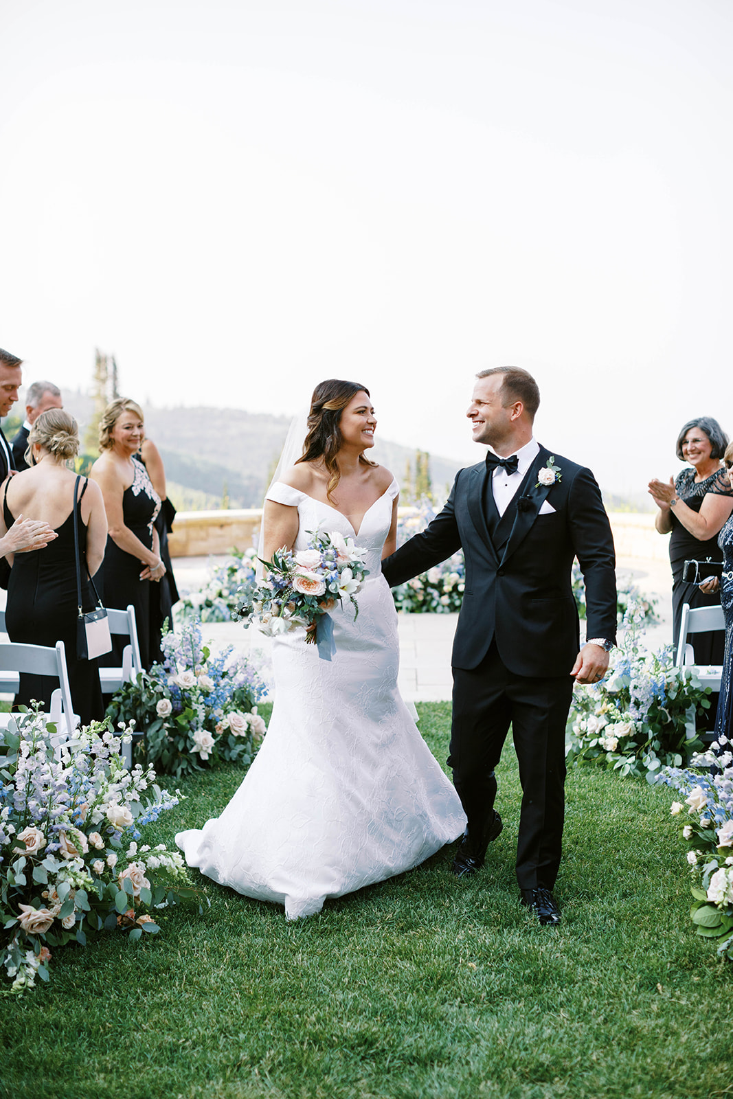 a bride and groom smile at their loved ones after their garden theme wedding ceremony at montage deer valley resort in park city utah. photo by megan robinson photography