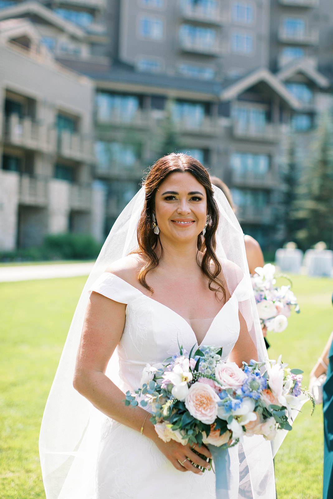 a bride poses with her bouquet wearing an off the shoulder lace wedding dress at her garden theme wedding in park city utah. photo by megan robinson photography
