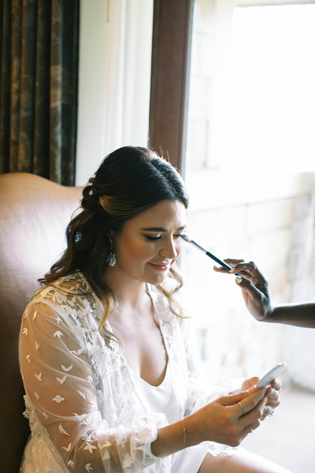 a bride getting her makeup done while getting ready for her garden party theme wedding in park city utah. photo by megan robinson photography