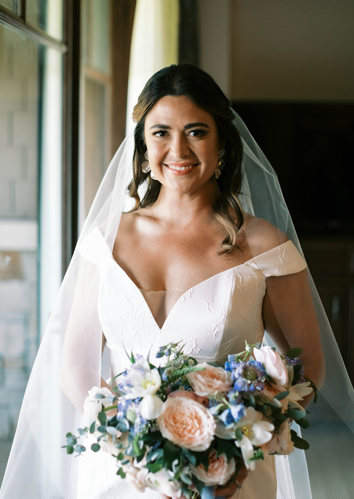 a bride poses with her bouquet wearing an off the shoulder lace wedding dress at her garden theme wedding in park city utah. photo by megan robinson photography