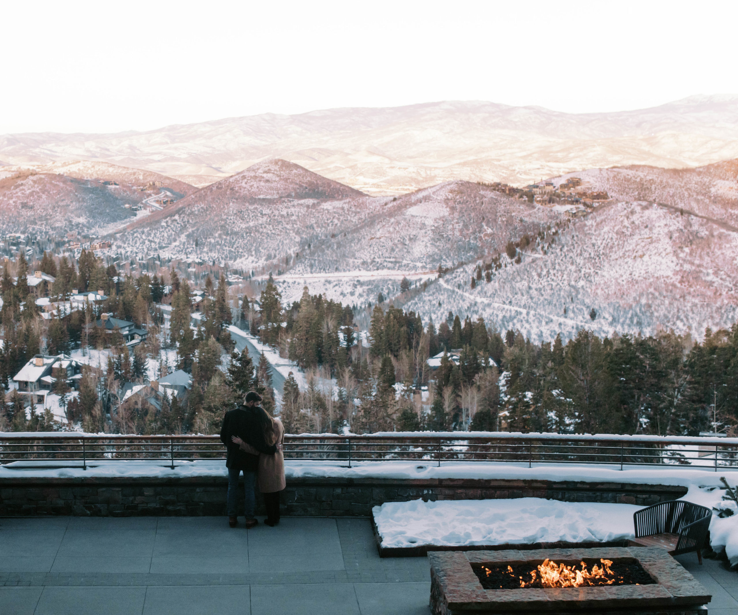 a couple overlooks the mountains of park city during their winter engagement photos in park city. photo taken by megan robinson photography