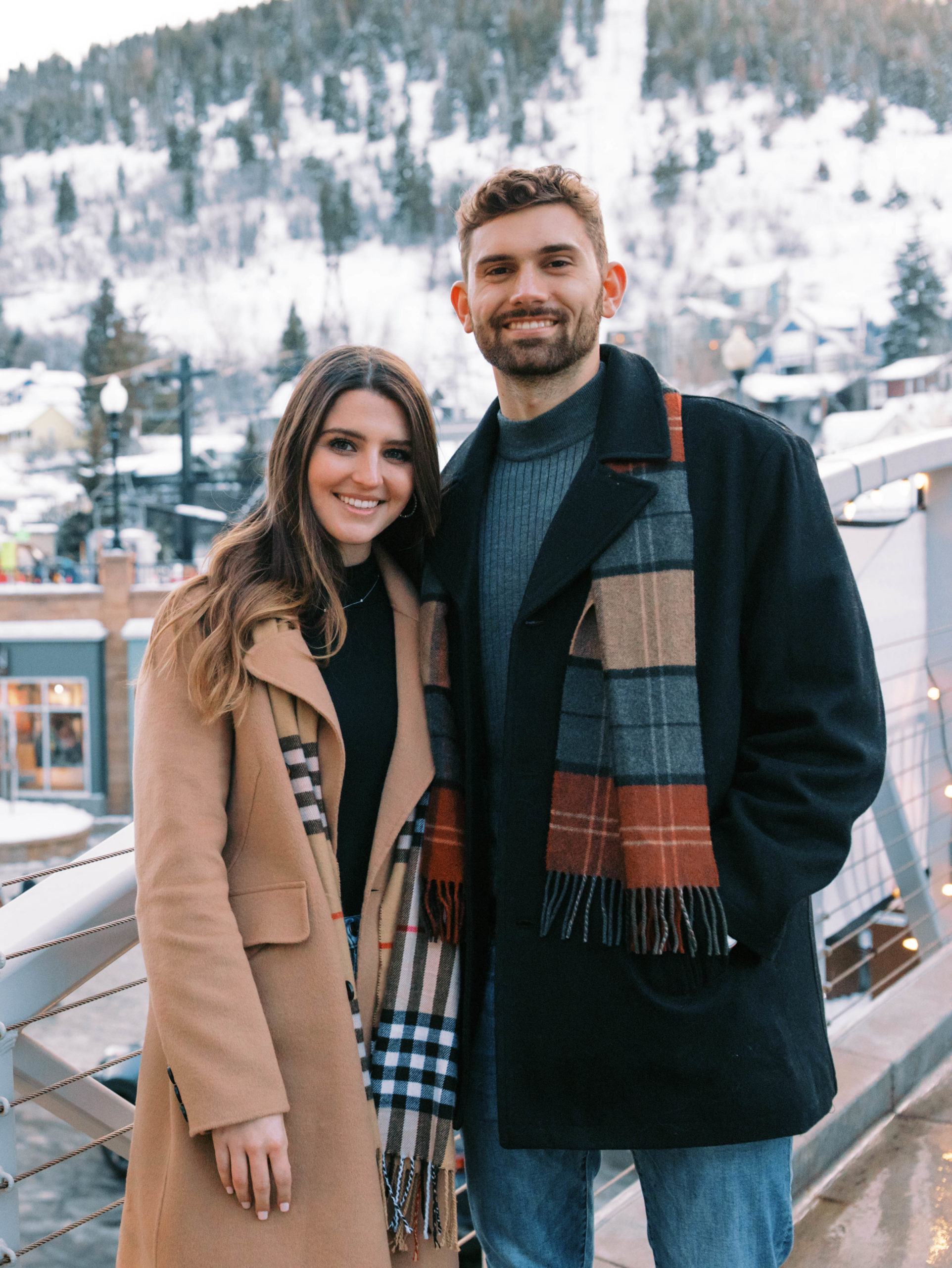 a couple smiles at the camera during winter engagement photos in downtown Park City, Utah. photo taken by Megan Robinson Photography 