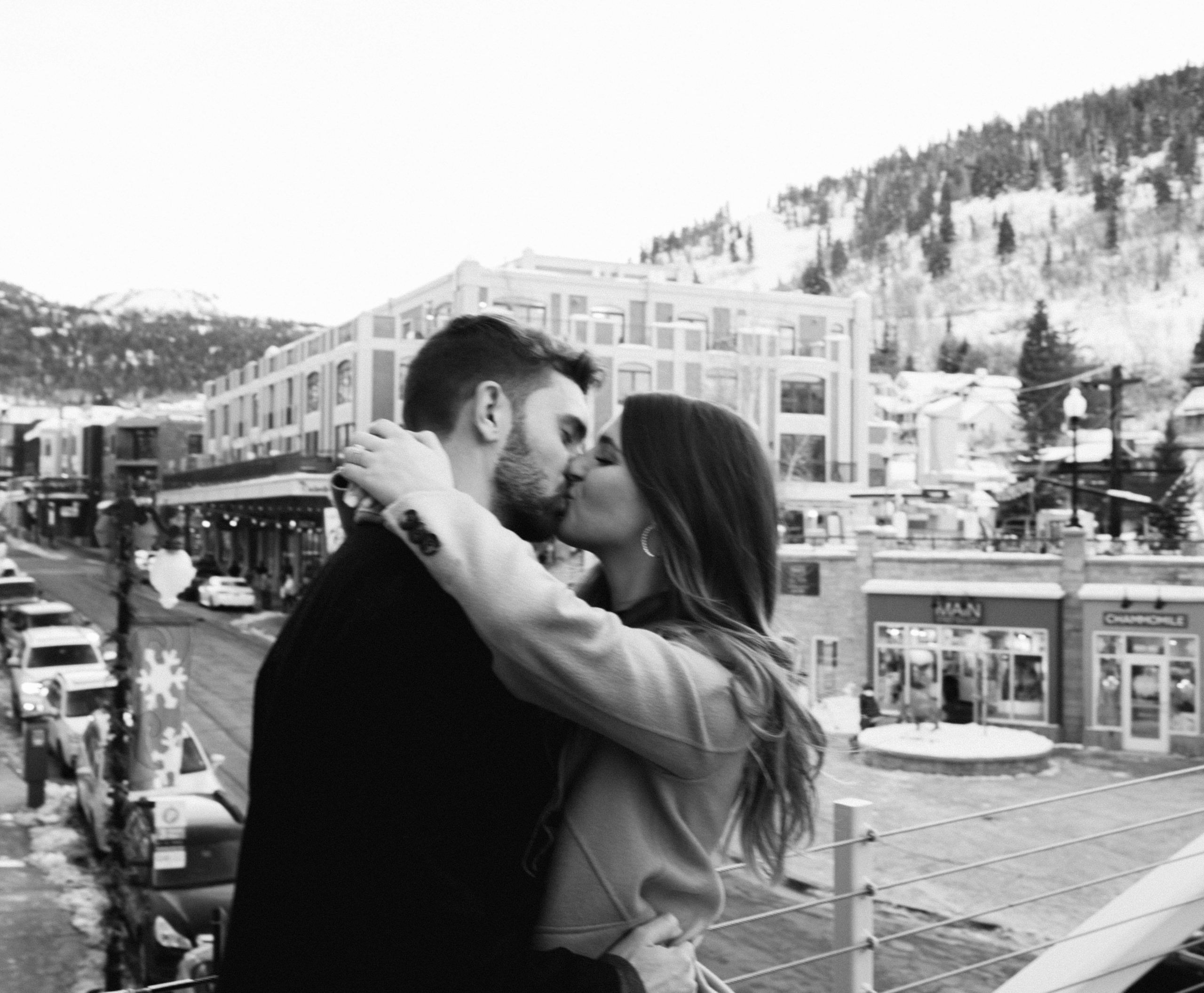 a couple kisses during city winter engagement photos overlooking downtown park city Utah. photo taken by Megan Robinson Photography