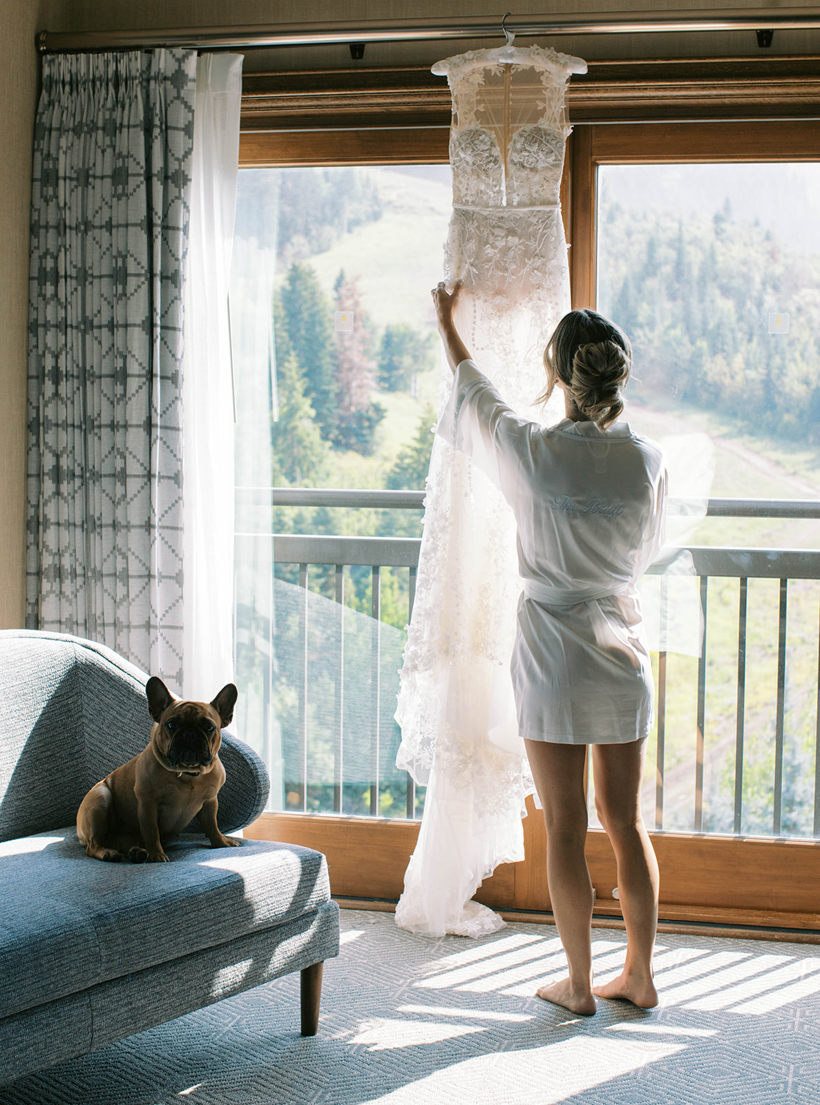 a bride looks at her wedding gown with views of the mountains in the background as she gets ready for her st regis deer valley wedding