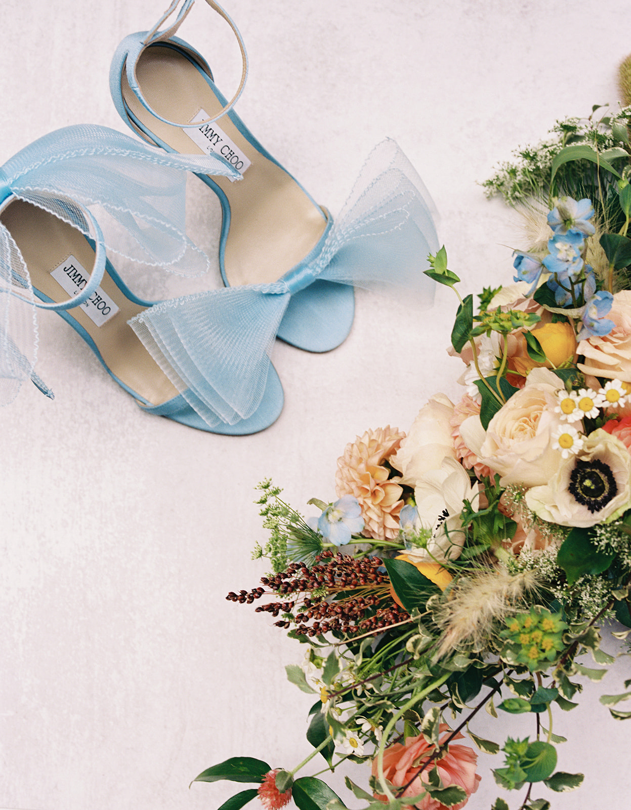 wedding detail shot of a bride's colorful wedding bouquet and blue jimmy choo shoes 