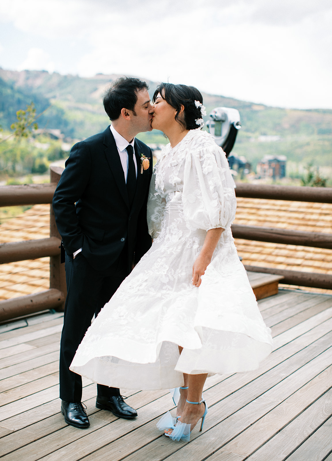 a couple kisses at their late summer wedding in park city utah with mountains in the background