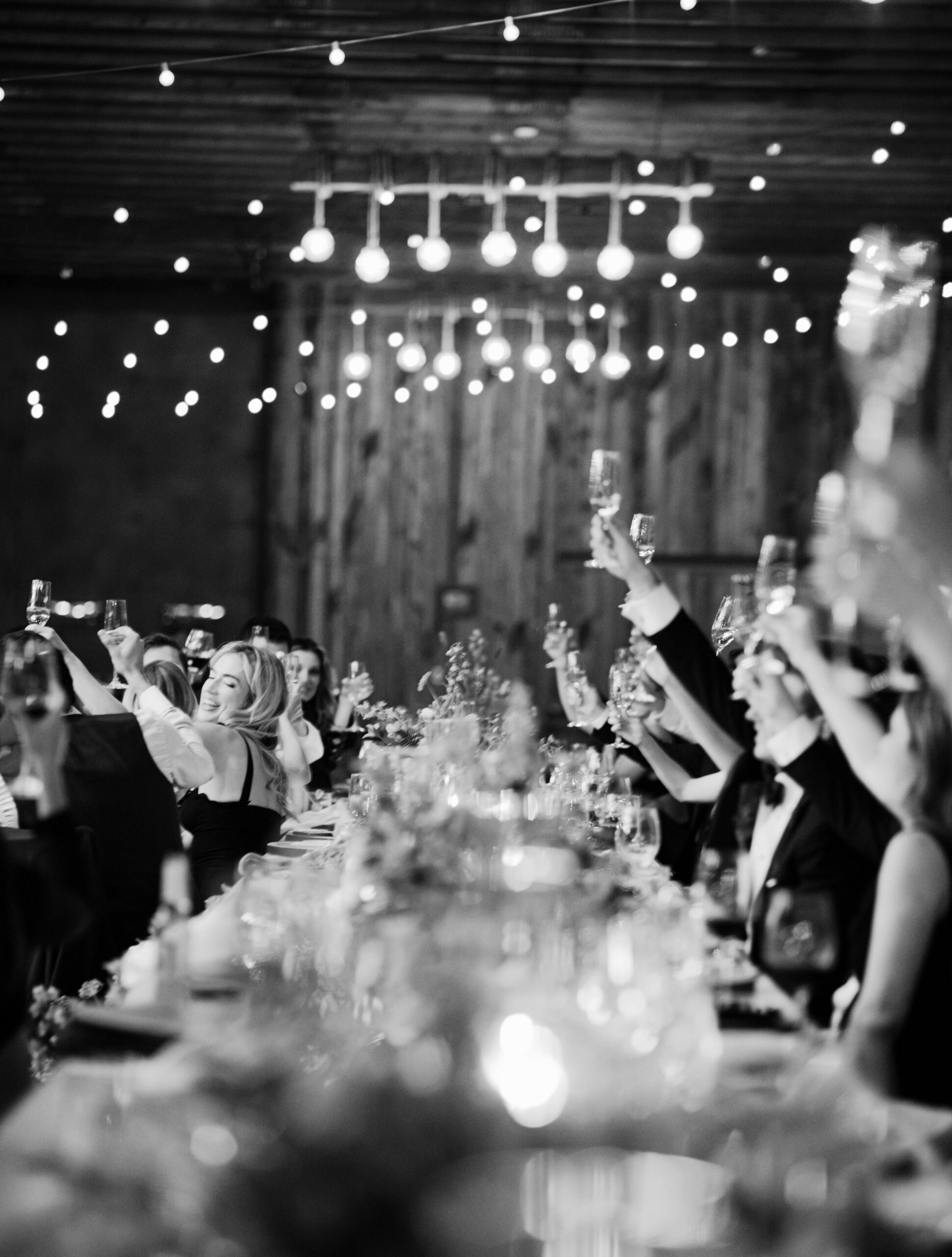 wedding guests at an indoor reception at The Lodge at Blue Sky in Park City, Utah raise their glasses for a toast to the bride and groom