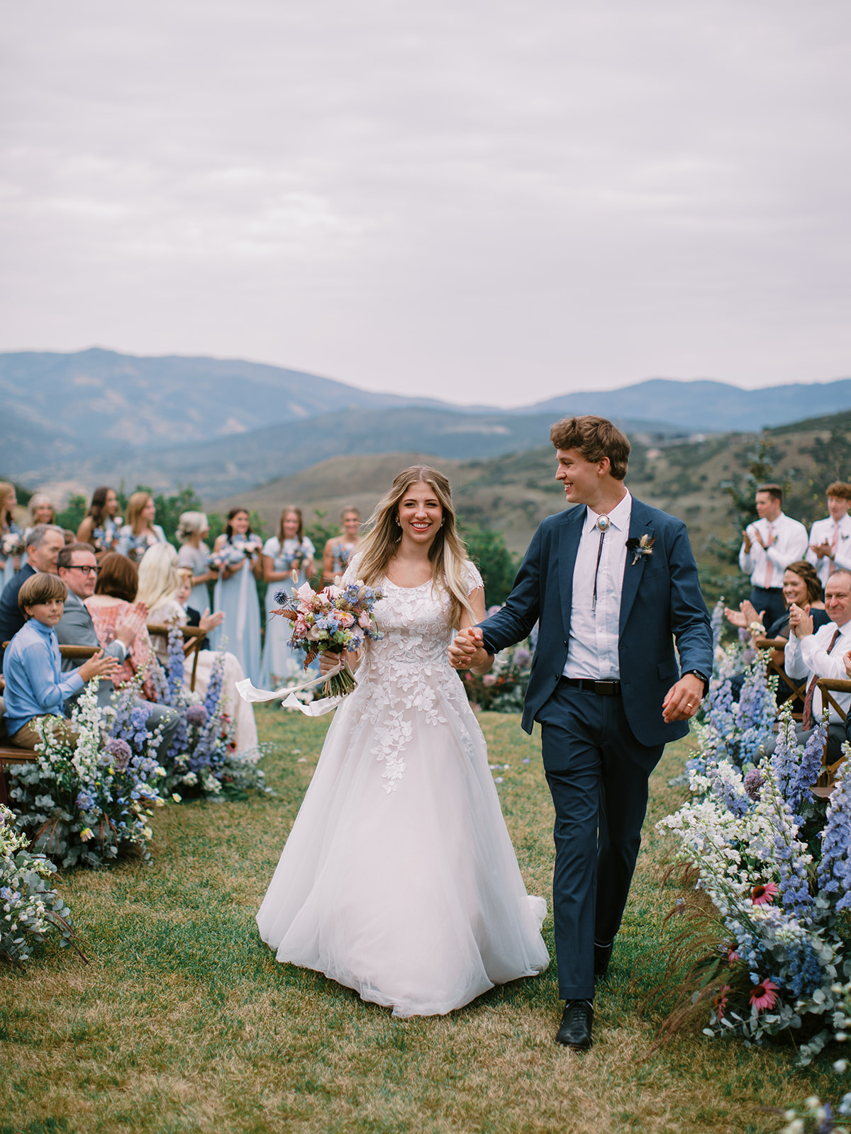 a couple walks up the aisle just married with the mountains in the background at their park city wedding ceremony