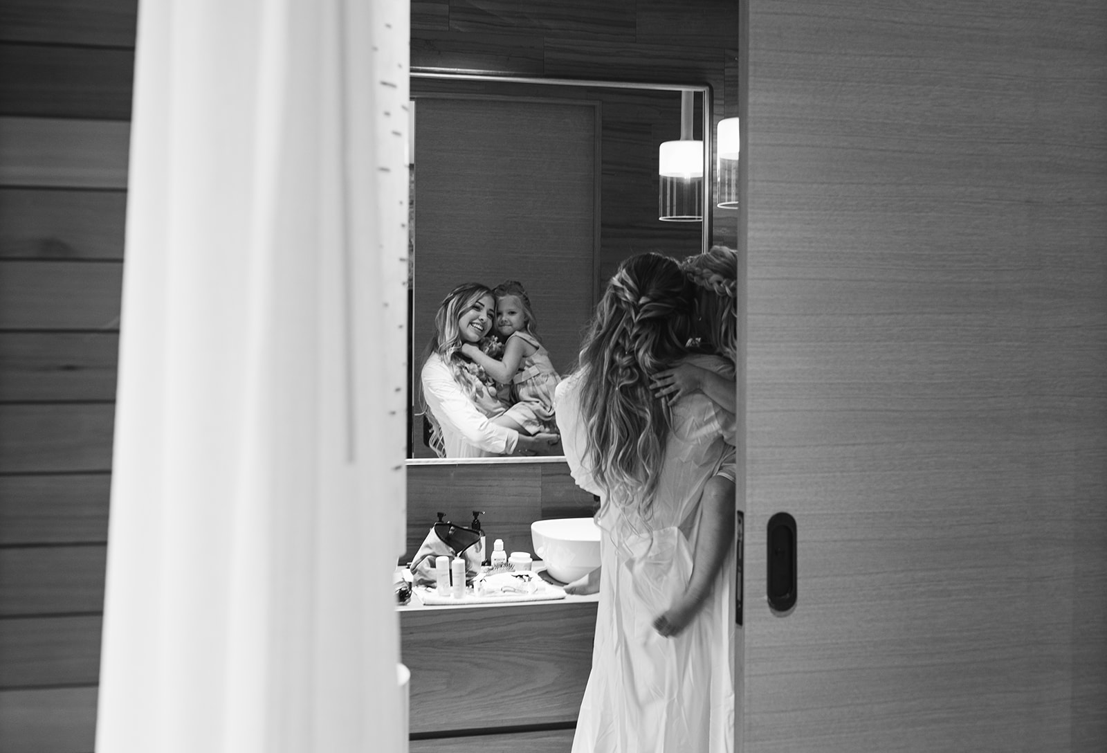 a bride poses in the mirror with her flower girl the morning of her park city wedding in utah