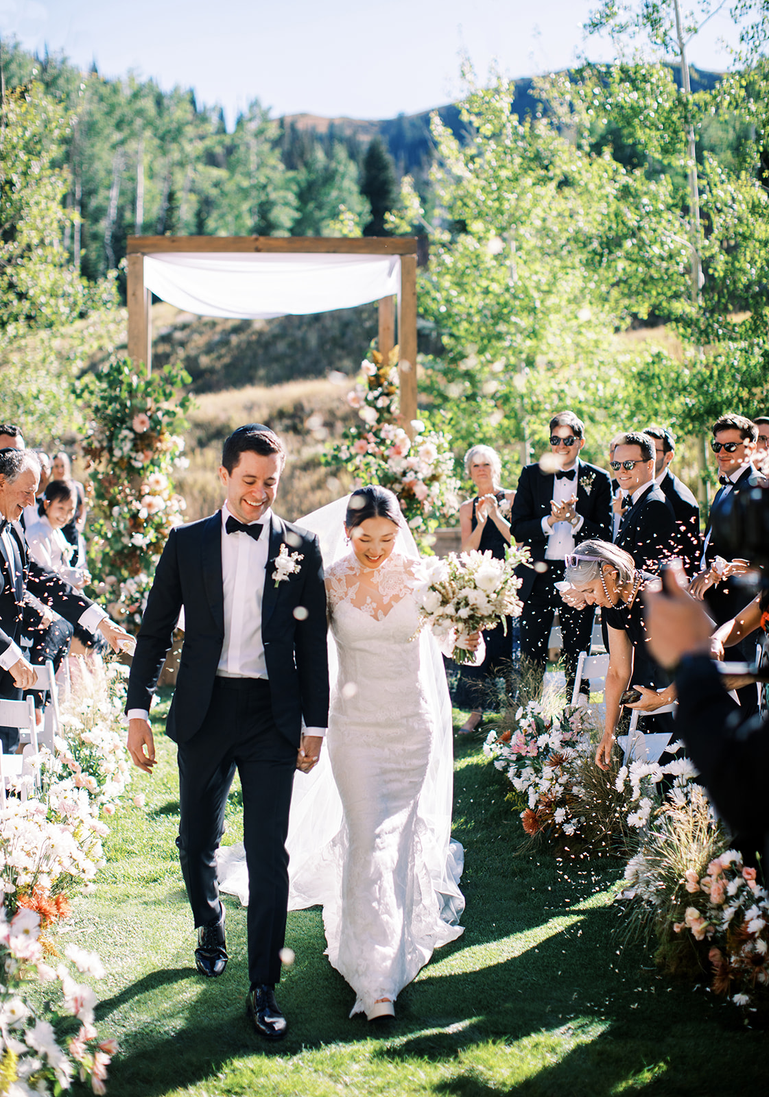 young couple walking up the aisle after wedding ceremony with guests throwing flower petals