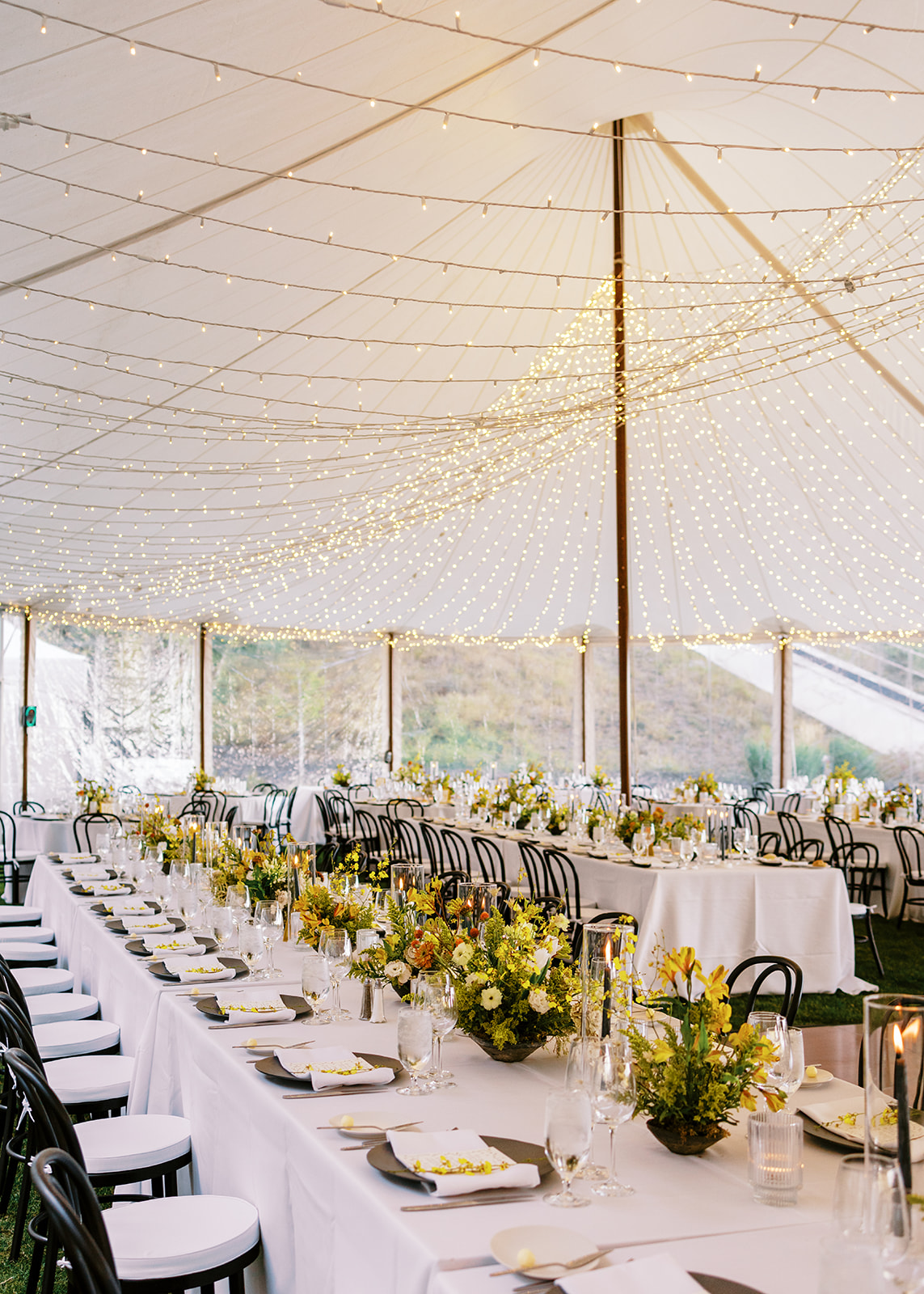 wedding reception under tent with string lights and flower centerpieces 