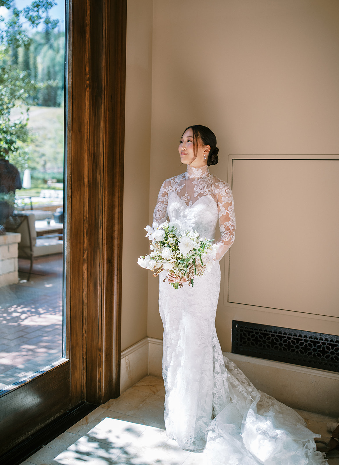 bride poses in a long sleeve lace wedding dress with white bridal bouquet 