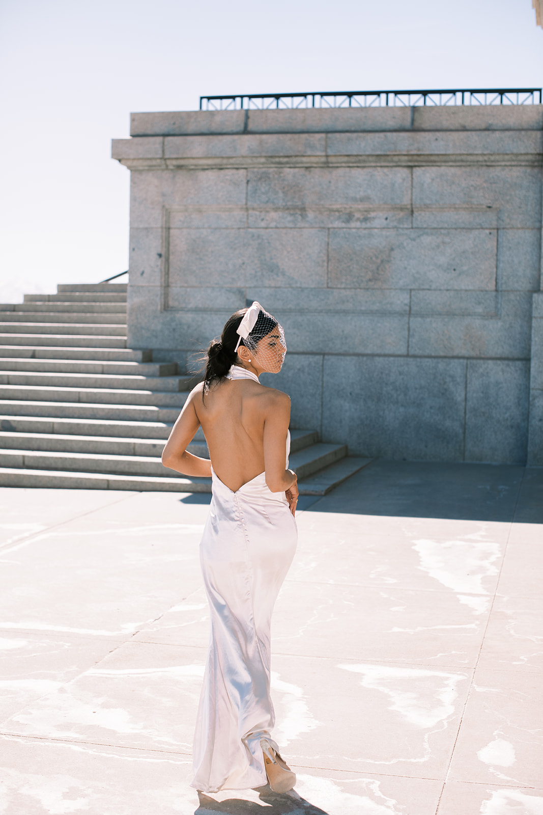 a bride poses in a silk wedding dress outside the utah capitol building