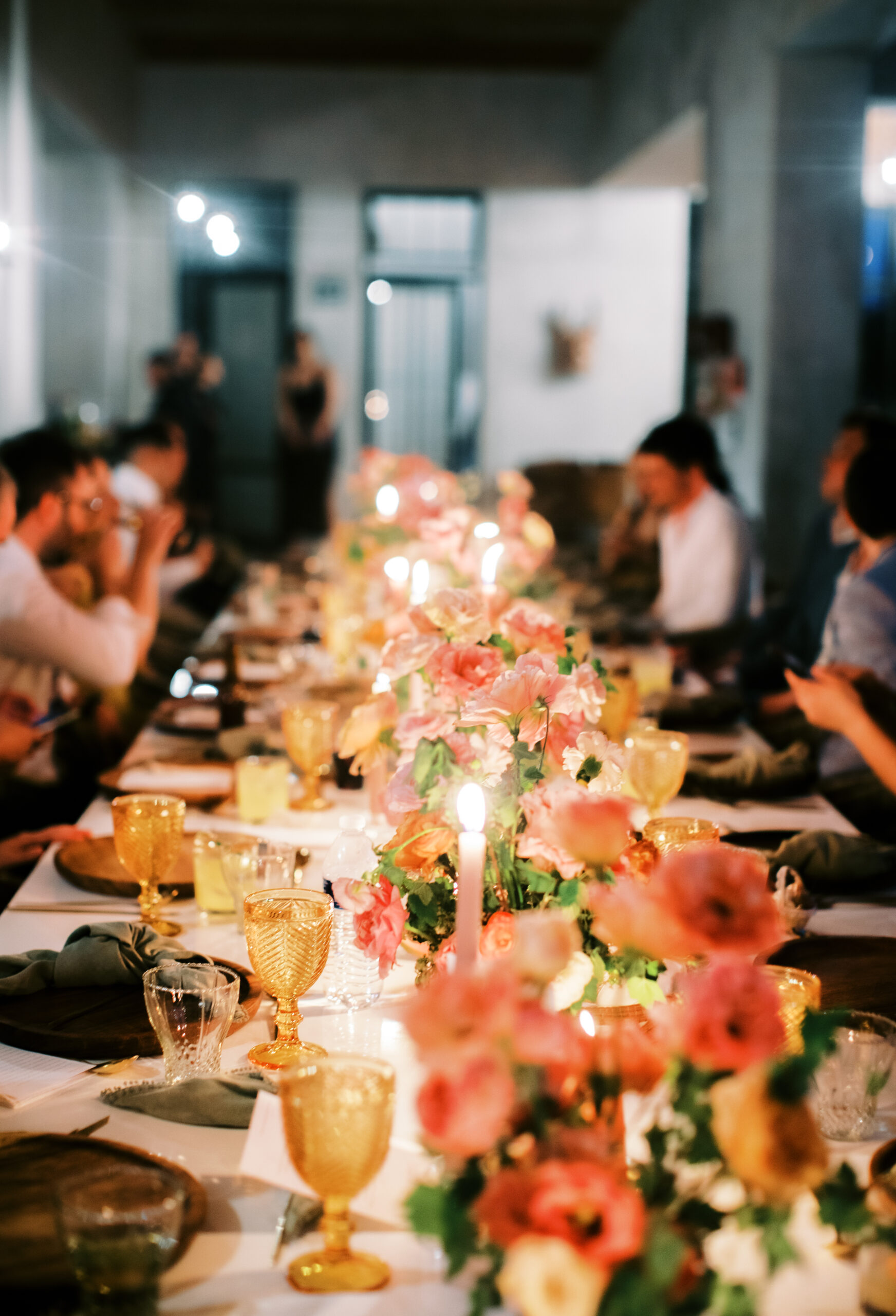 a close up of a beautiful tablescape of pink and orange colors, with candles lit and amber glasswear 