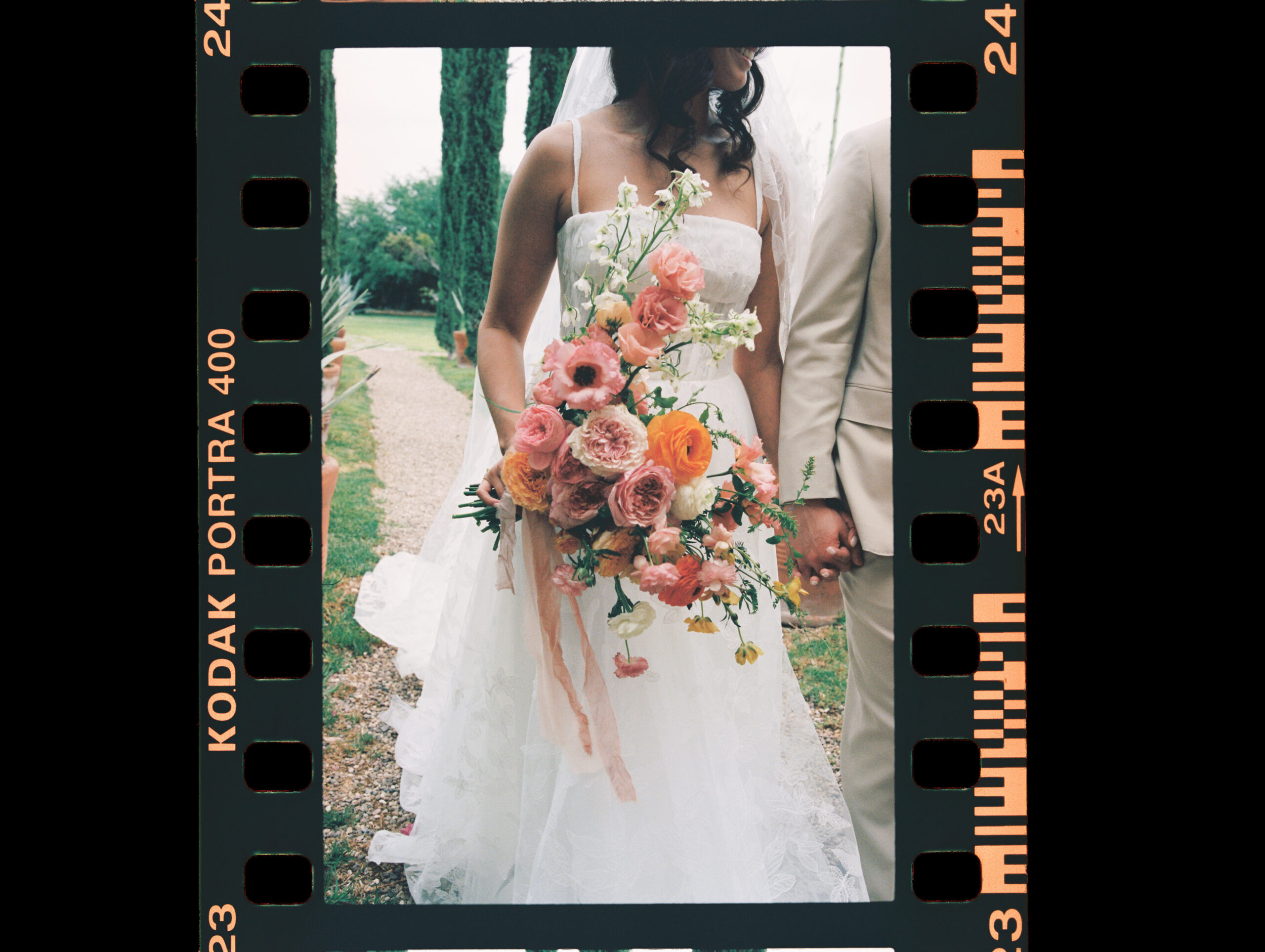 a film photo of a bride holding a bouquet and holding her groom's hand